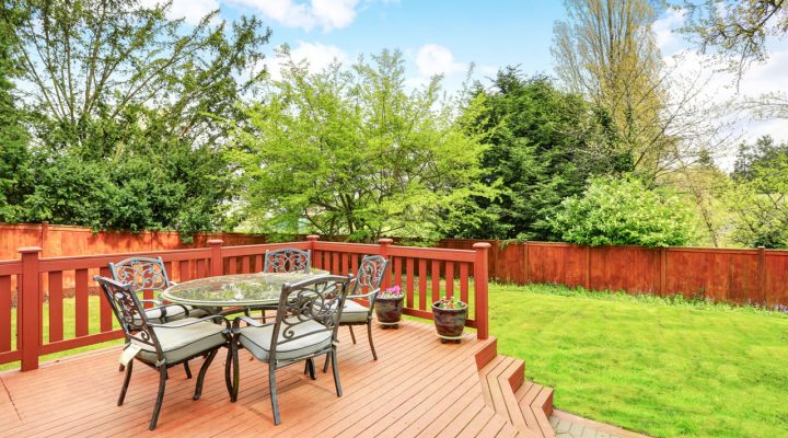 beautiful deck with small dining area at the backyard of a house with fence