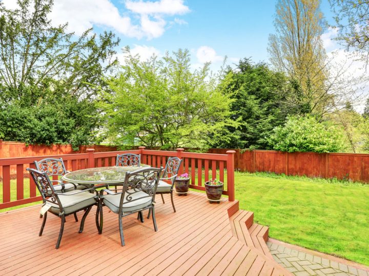 beautiful deck with small dining area at the backyard of a house with fence