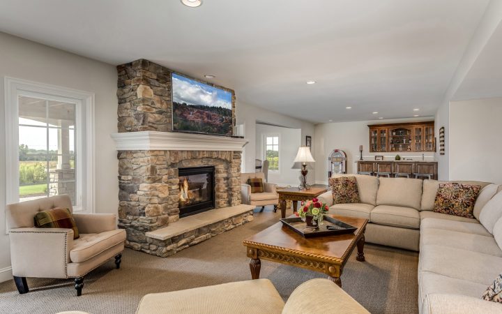 home renovated, livingroom with carpet and a big couch in front of the fireplace, a minibar and jukebox at the background