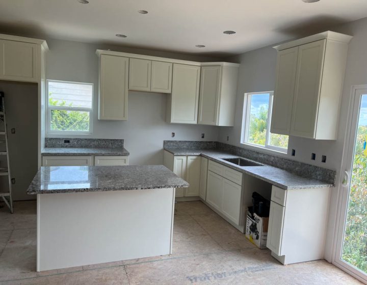 a kitchen renovated with granite countertop, white painted cabinets and an island